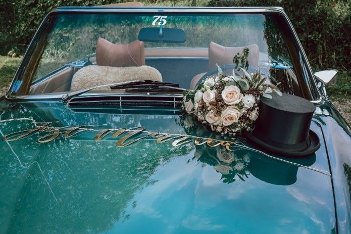 Ein Auto mit einem Blumenstrauß und einem Zylinder auf der Motorhaube.