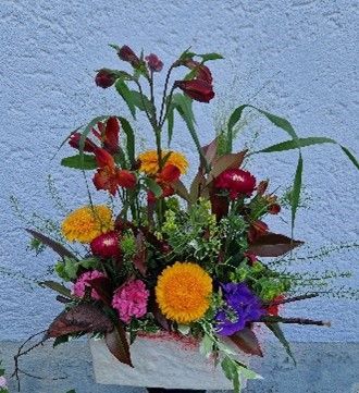 Eine Vase gefüllt mit Blumen und Blättern vor einer blauen Wand
