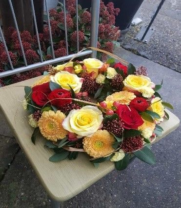 Auf einem Holztisch steht ein Blumenkranz.