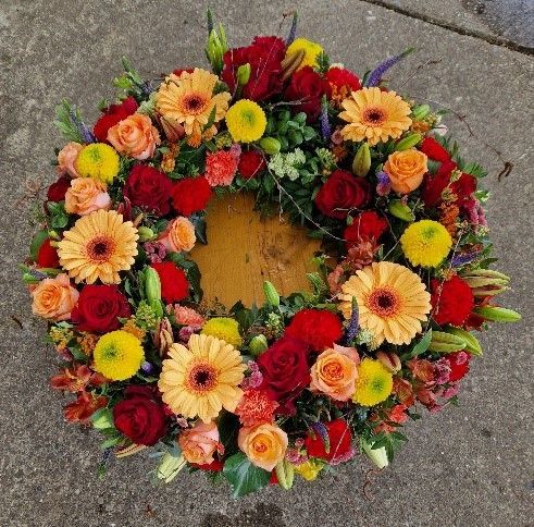 Auf einer Betonfläche liegt ein Blumenkranz.