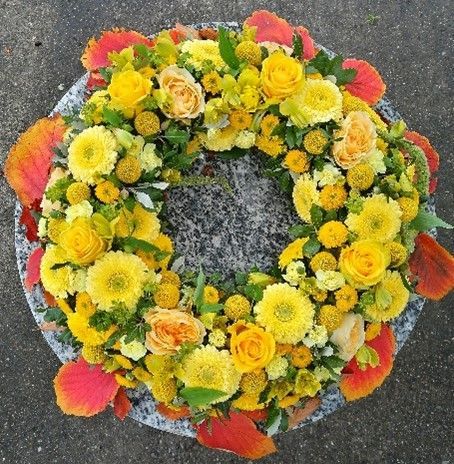 Ein Kranz aus gelben Blumen liegt auf dem Boden