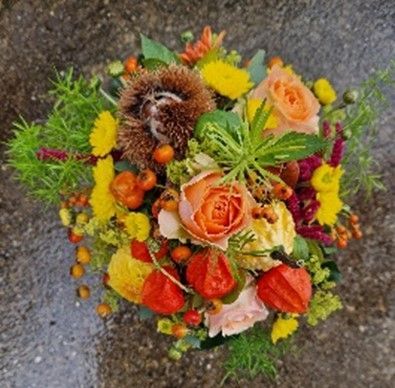 Ein Strauß Blumen und Beeren auf einer Betonoberfläche