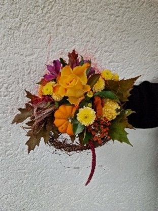 Eine Person hält einen Blumenstrauß vor einer weißen Wand