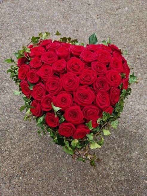 Ein herzförmiges Arrangement aus roten Rosen und Grünpflanzen
