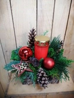 In der Mitte eines Weihnachtsgestecks steht eine Kerze.