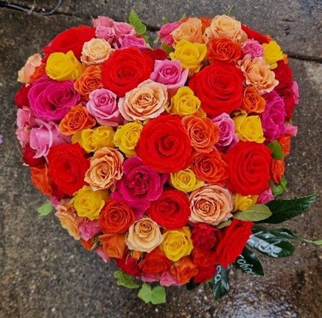 Ein herzförmiger Strauß aus roten, rosa und gelben Rosen