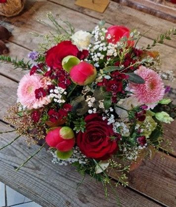 Auf einem Holztisch steht ein Blumenstrauß.