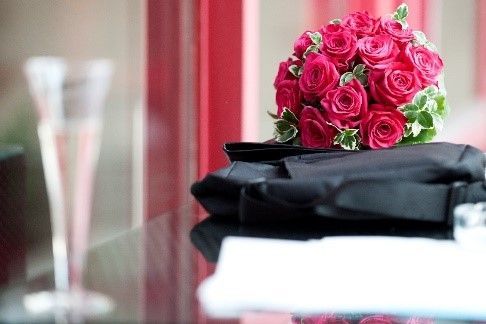 Ein Strauß rosa Rosen liegt auf einer schwarzen Aktentasche auf einem Tisch.