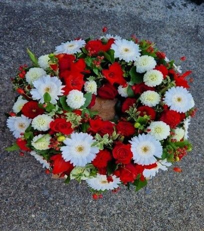 Ein Kranz aus roten und weißen Blumen auf dem Boden