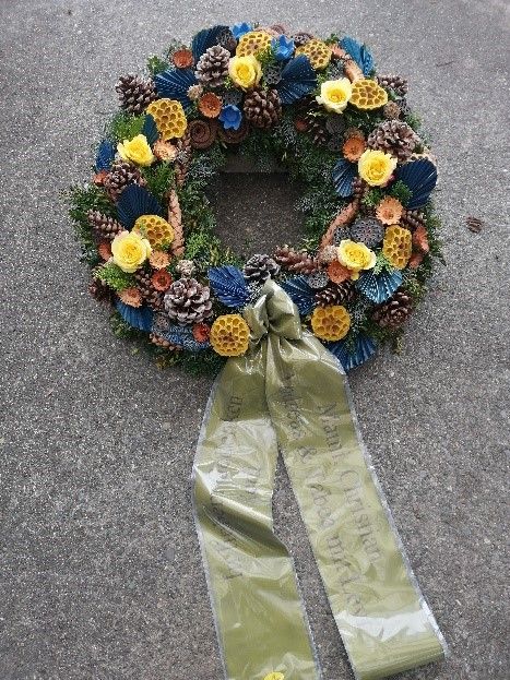 Ein Kranz mit Tannenzapfen, Blumen und einem grünen Band