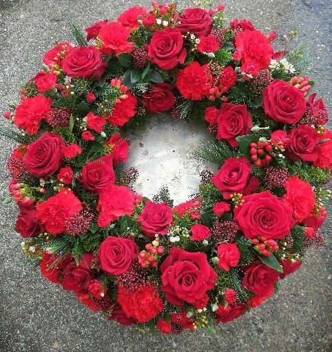 Auf dem Boden liegt ein Kranz aus roten Rosen und Nelken.