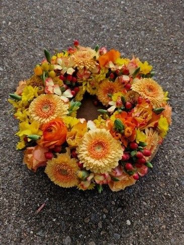Auf dem Boden liegt ein Kranz aus gelben und orangefarbenen Blumen.