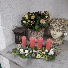 Eine Statue einer Frau, umgeben von Blumen und Kerzen