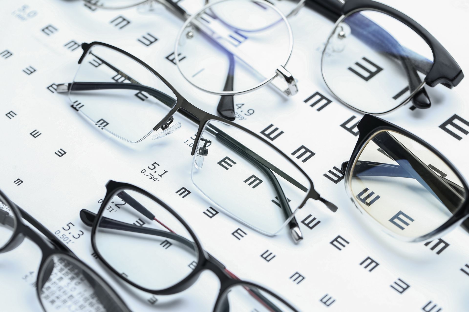 Gafas y gafas de sol dispuestas sobre un fondo blanco con un patrón repetido de la letra E.