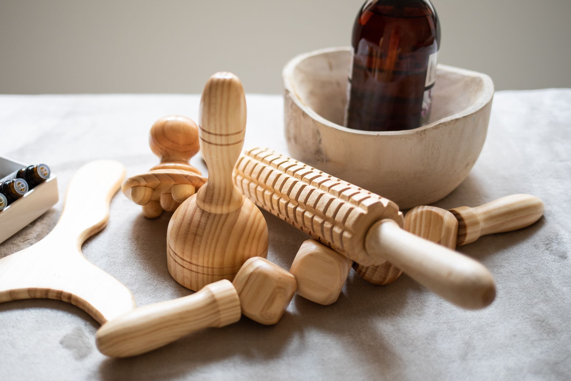 Un rodillo de madera se encuentra sobre una mesa al lado de un recipiente con aceite.
