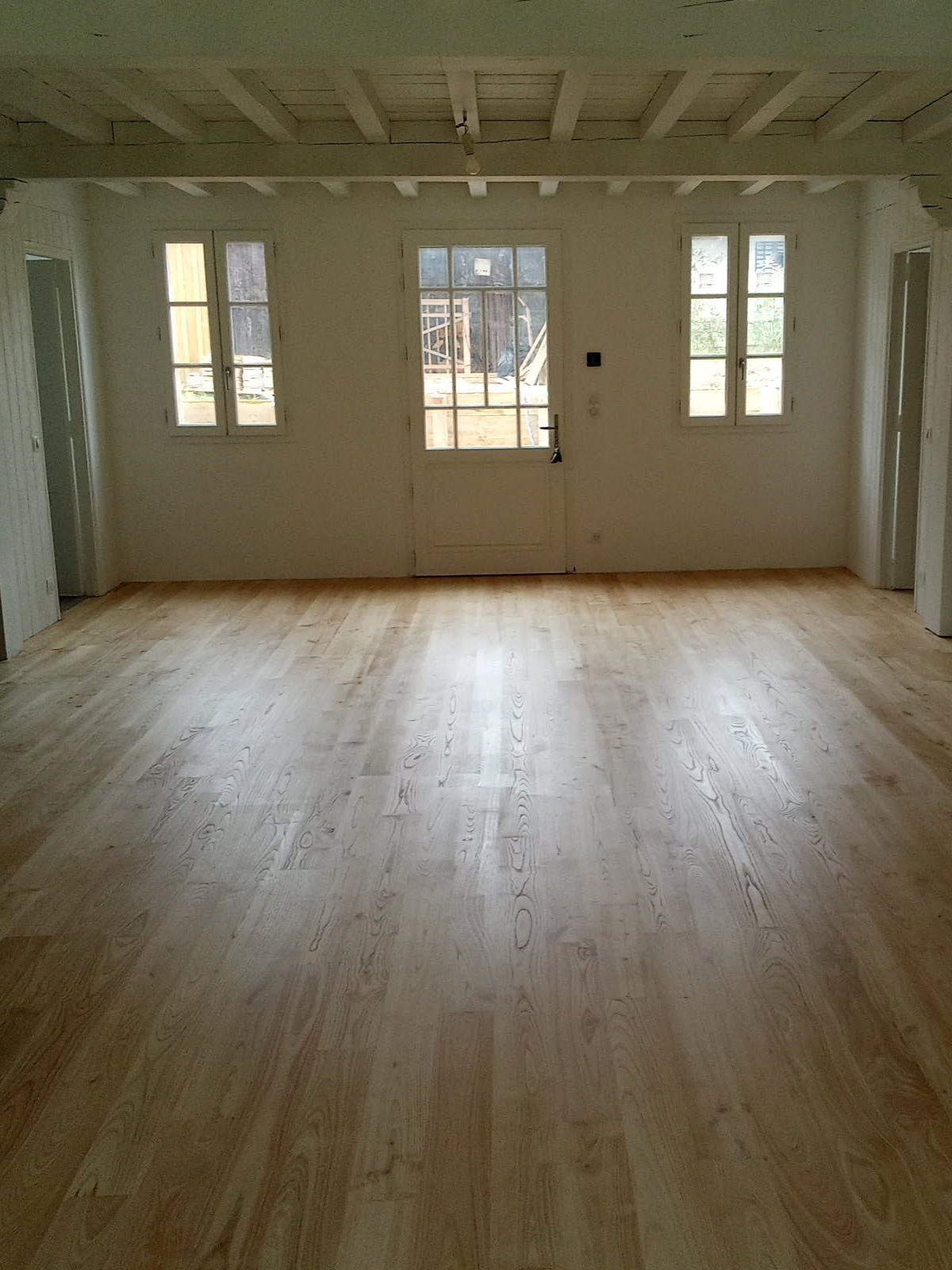 Parquet en cours de rénovation avec une finition transparente ; motif parquet, certaines zones humides.