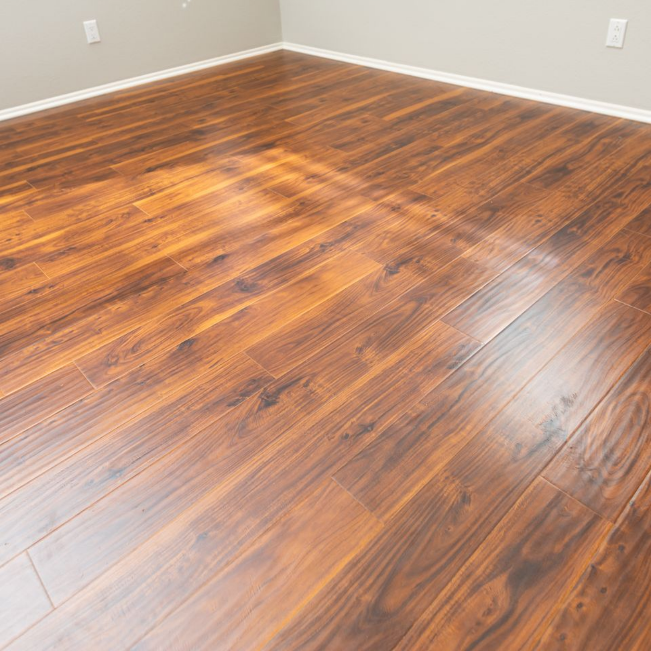 Pièce vide avec parquet foncé, murs gris et fenêtres à volets.