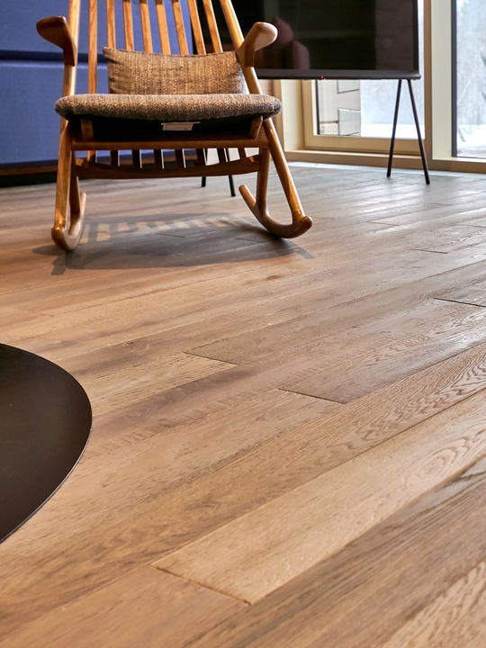 Sol en bois avec un fauteuil à bascule et un téléviseur.