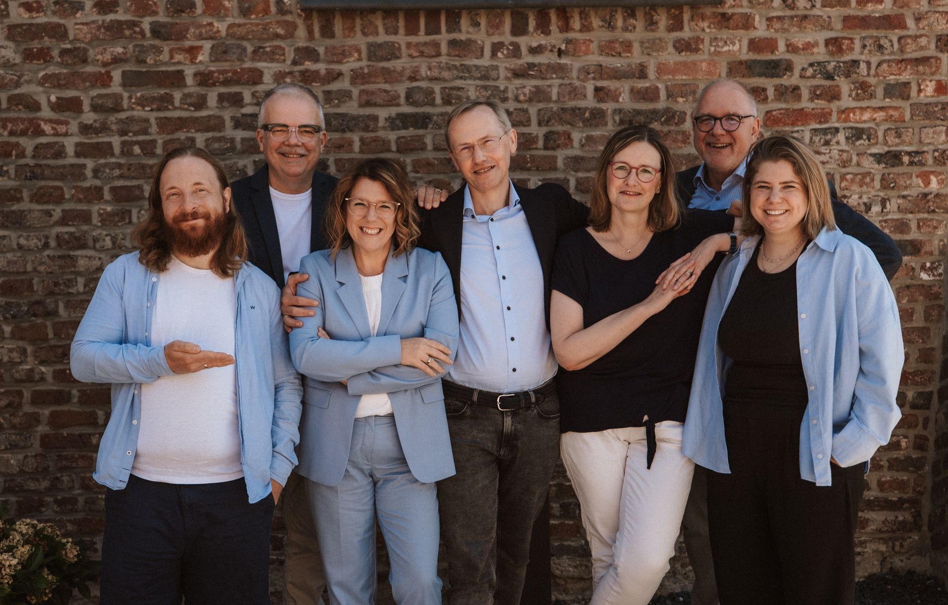 Sechs Pastoren in schwarzen Roben stehen vor einem hellblauen Kreuzlogo mit einem Text über kirchliche Zusammenarbeit, Fusion und Weltraum.