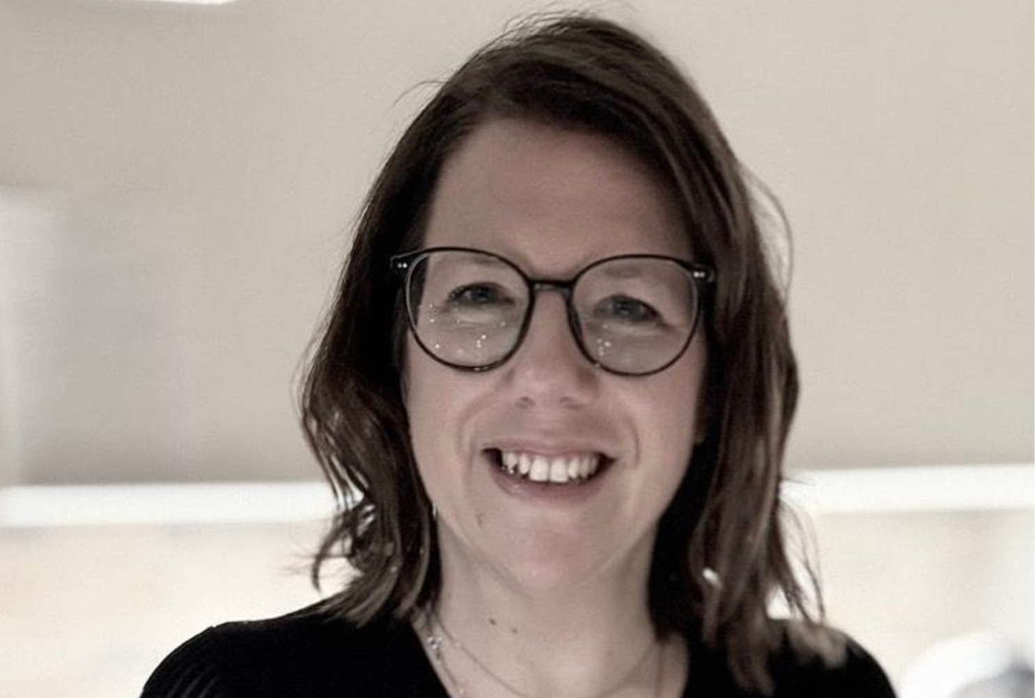 Eine Frau mit lockigem Haar lächelt in die Kamera.