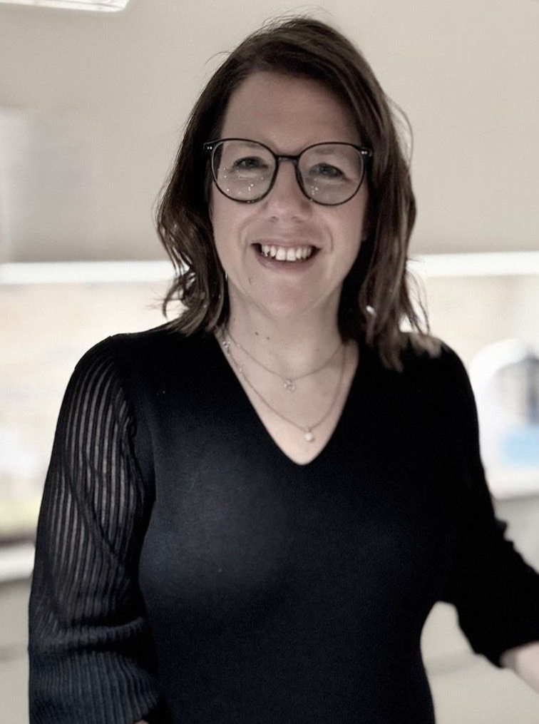 Ein Mann mit Bart lächelt und trägt ein weißes Hemd.