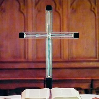 Ein klares Kreuz sitzt auf einer offenen Bibel