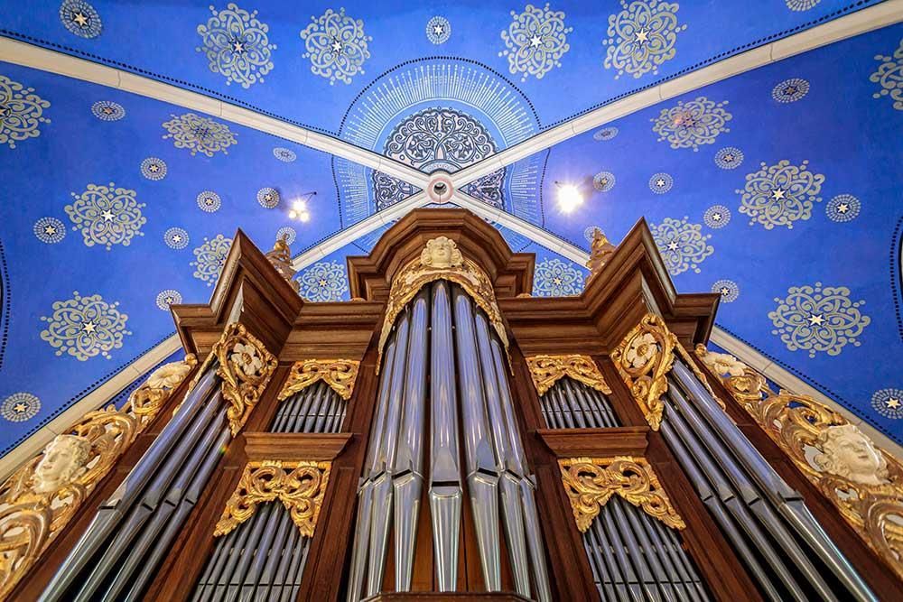 Blick nach oben auf die Orgel in einer Kirche mit blauer Decke