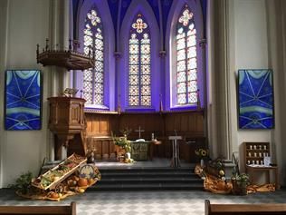 Das Innere einer Kirche mit violetten Fenstern und einem Podium.