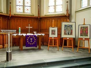 Eine Kirche mit Podium, Altar und Gemälden auf Staffeleien.