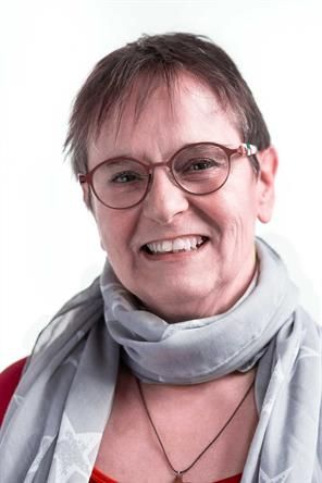Eine Frau mit Brille und Schal lächelt in die Kamera.
