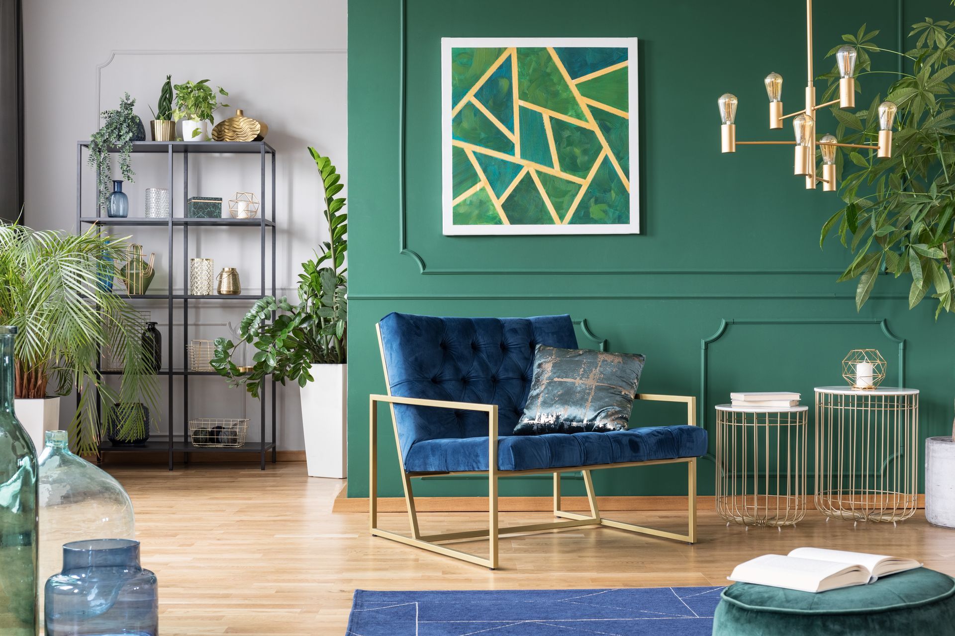 Salon moderne avec un mur d'accent vert, un canapé bleu, un fauteuil doré et des plantes d'intérieur