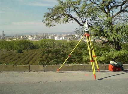 Un trípode está sentado al costado de una carretera con una ciudad al fondo.