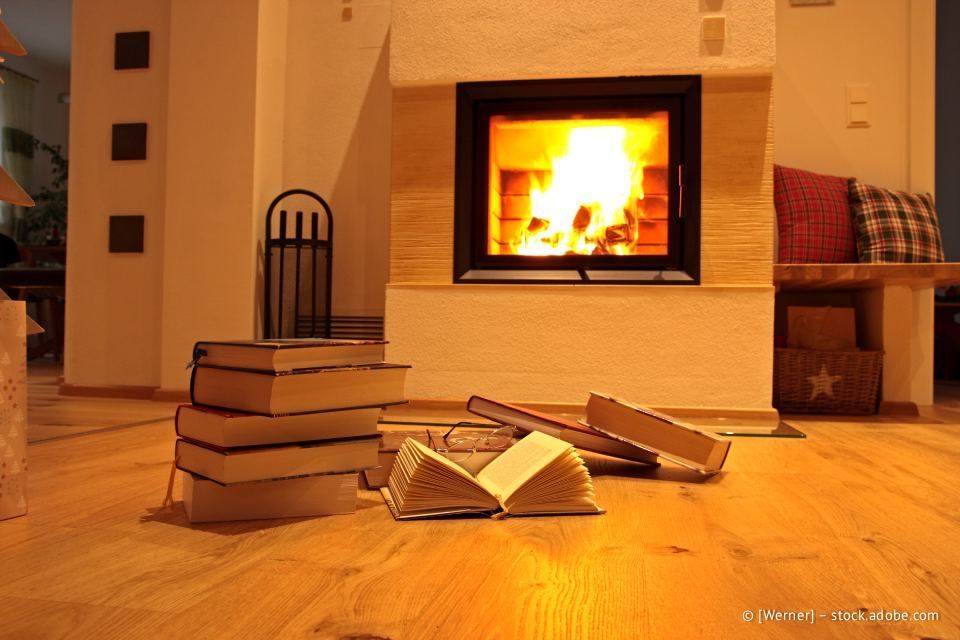 Geschmolzenes Metall ergießt sich aus einem Ausguss, industrielle Umgebung. Zwei Arbeiter im Hintergrund. Oranger Schein und Funken.