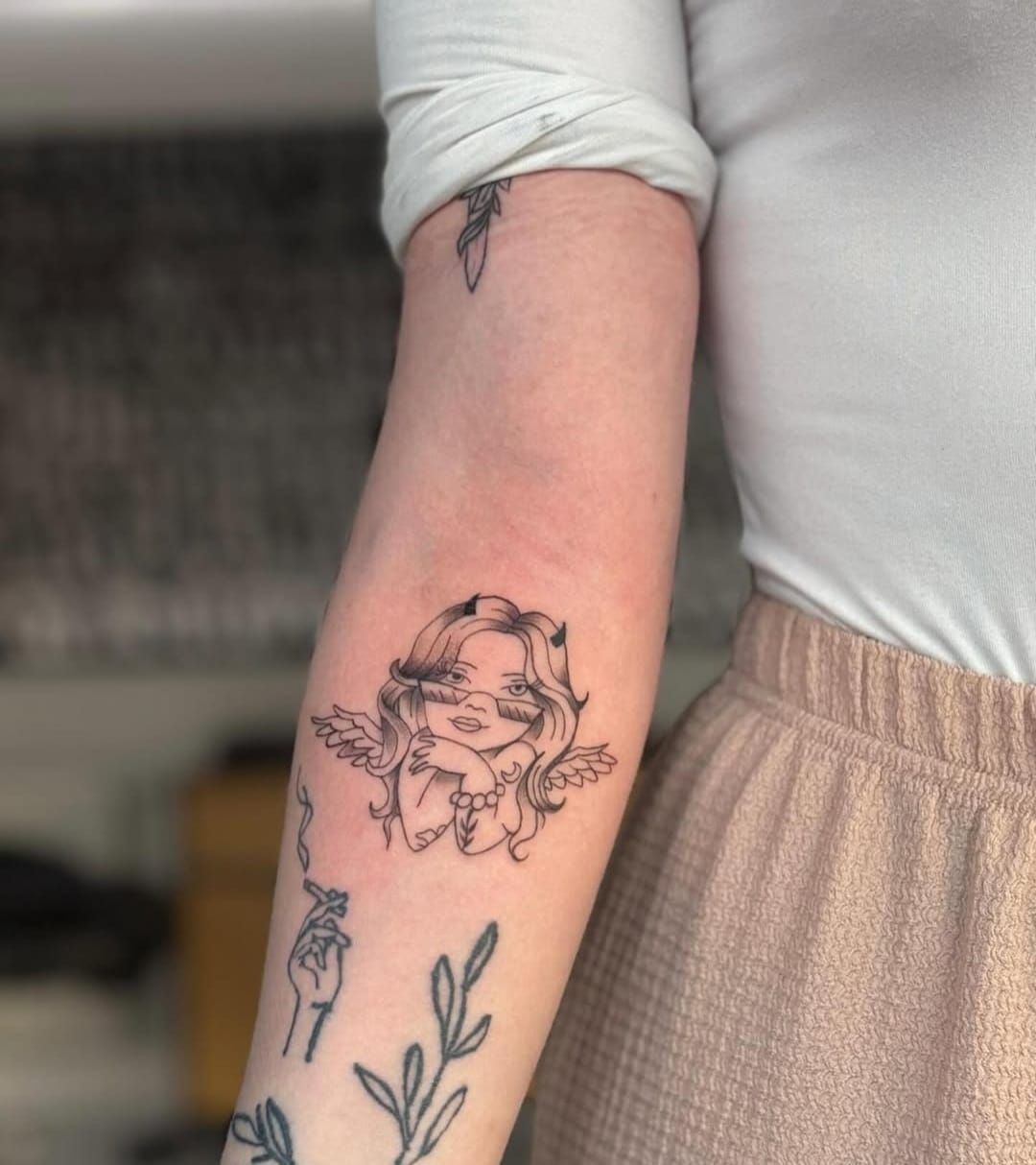 Eine Frau hat ein Engelstattoo auf ihrem Arm