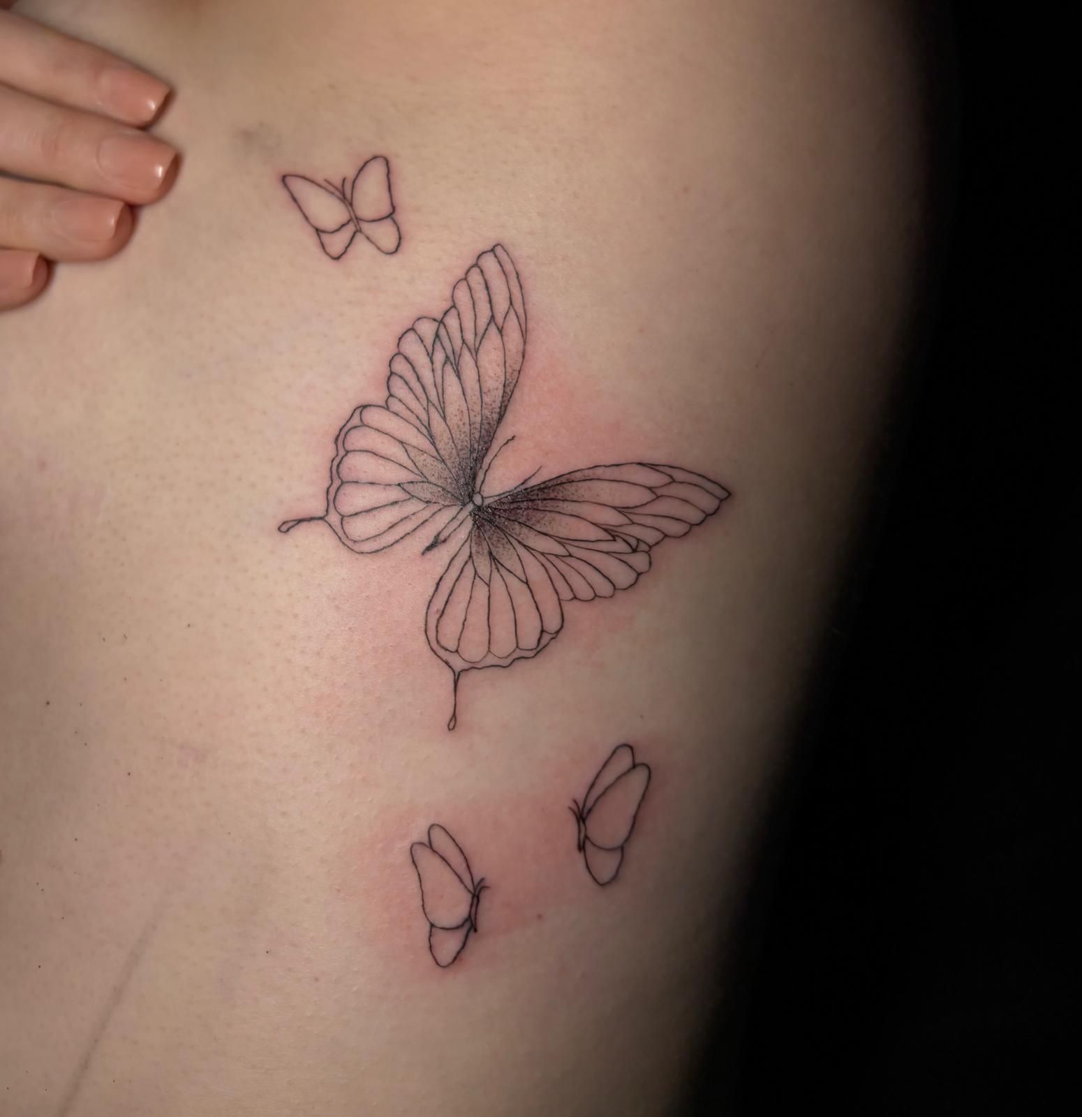 Eine Frau hat drei Schmetterlinge auf ihrer Seite tätowiert