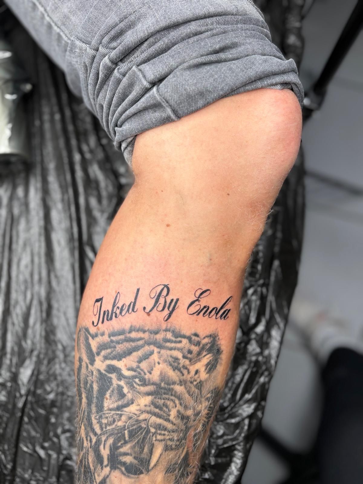 Eine Person hat ein Tattoo auf ihrem Bein, auf dem steht: „Inkreiert von Adler“