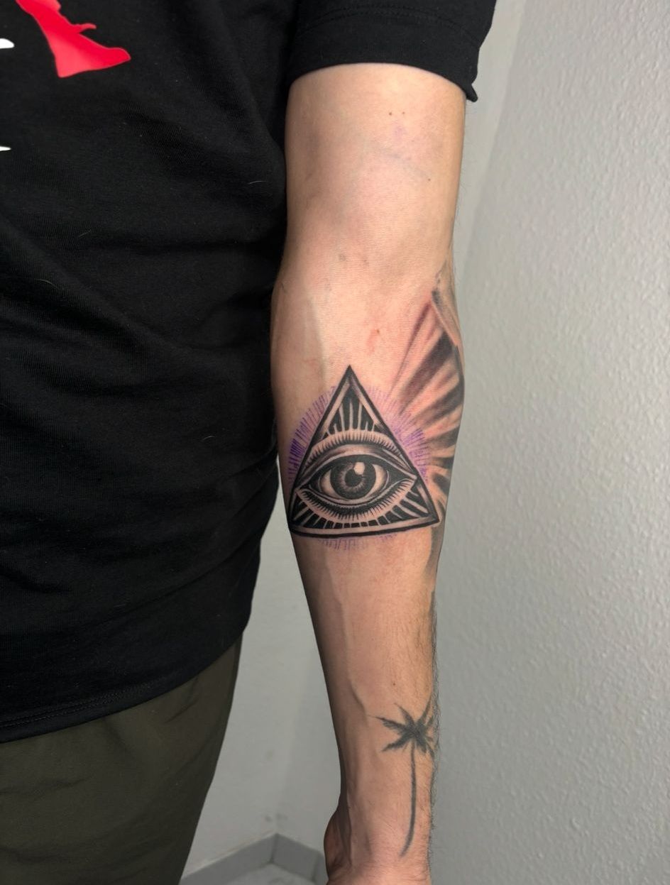 Ein Mann hat ein allsehendes Auge auf seinem Unterarm tätowiert