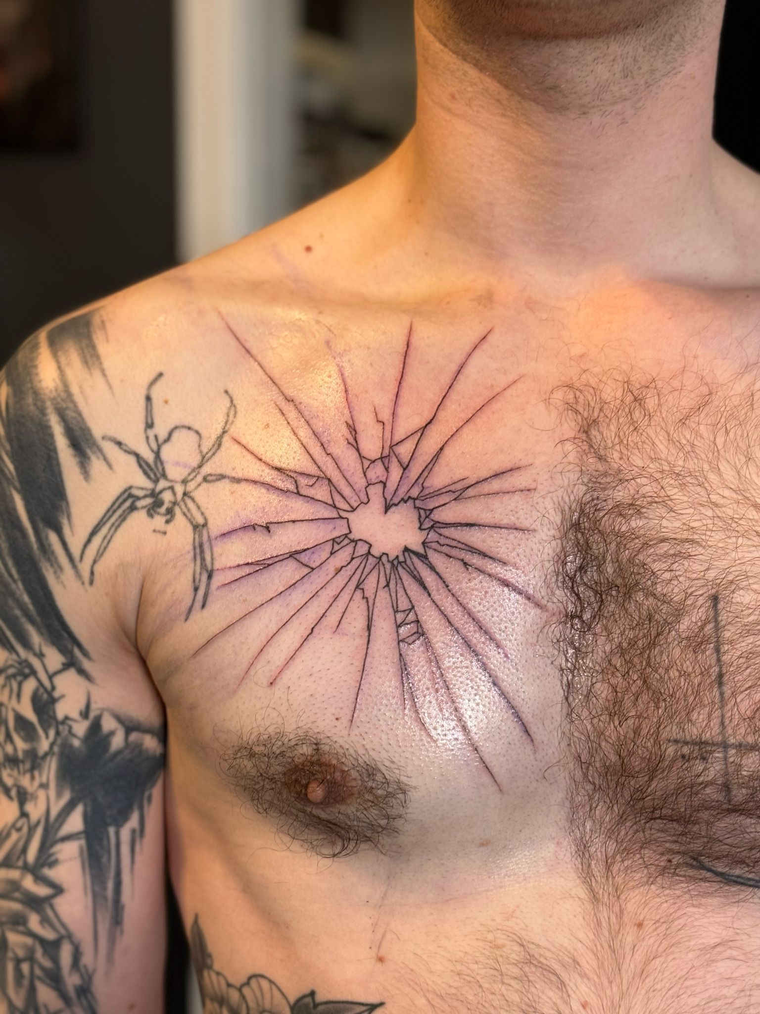 Ein Mann hat eine Spinnentätowierung auf seiner Brust