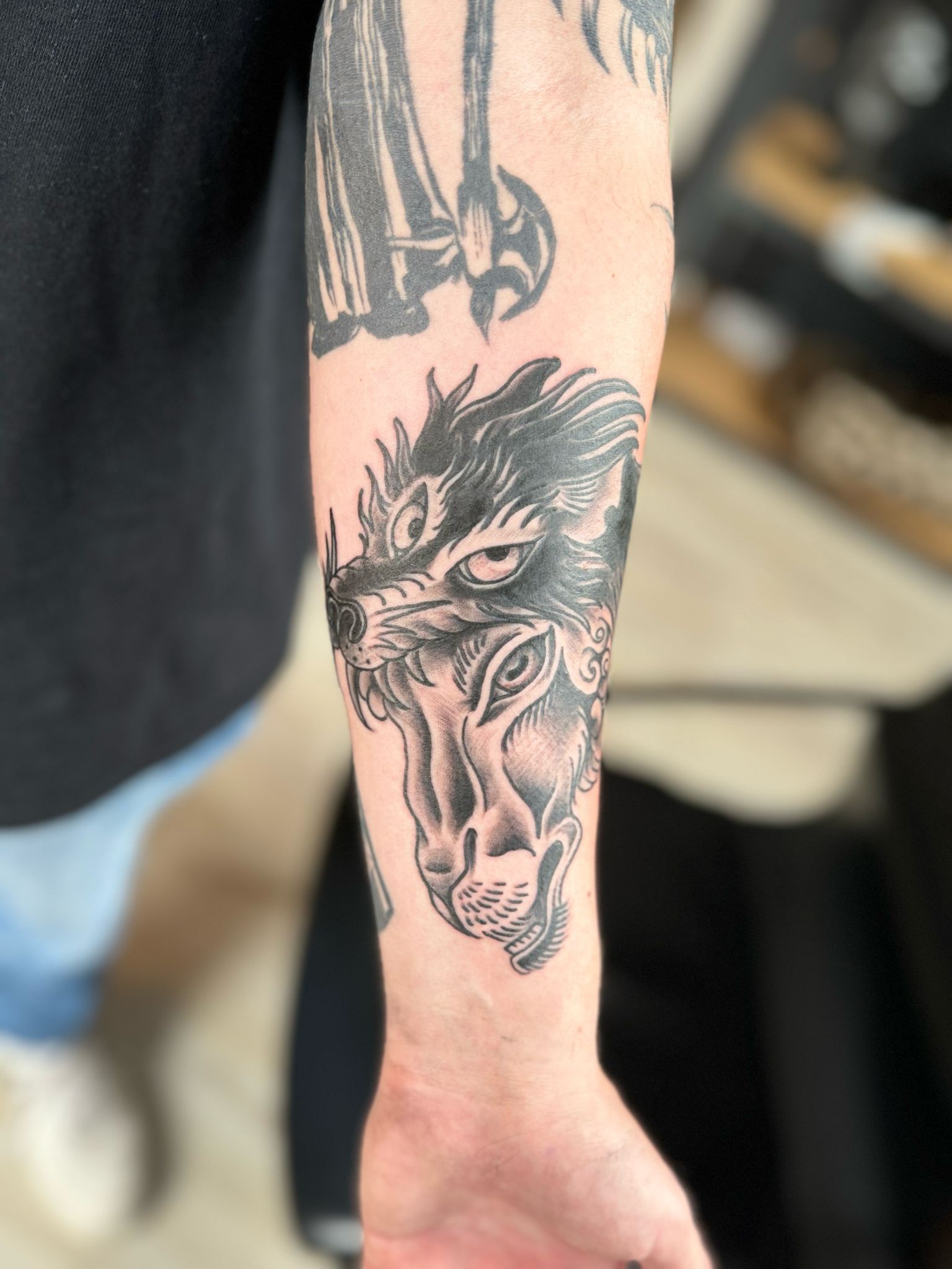 Ein Mann hat ein Wolfstattoo auf seinem Unterarm