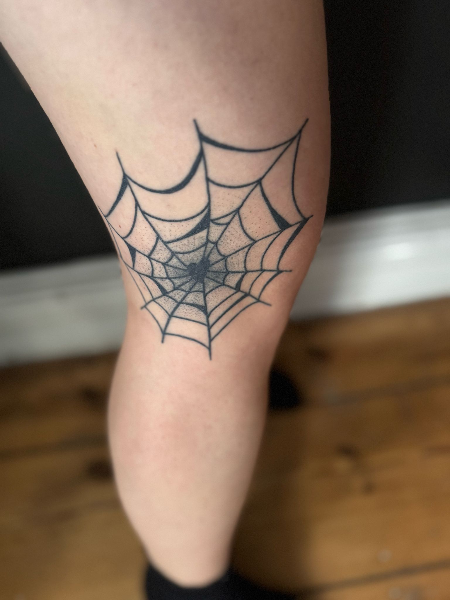 Eine Person hat ein Spinnennetz-Tattoo auf ihrem Knie.