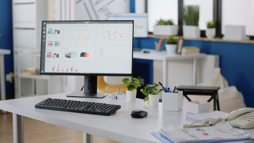 Un monitor de computadora y un teclado están sobre un escritorio en una oficina.