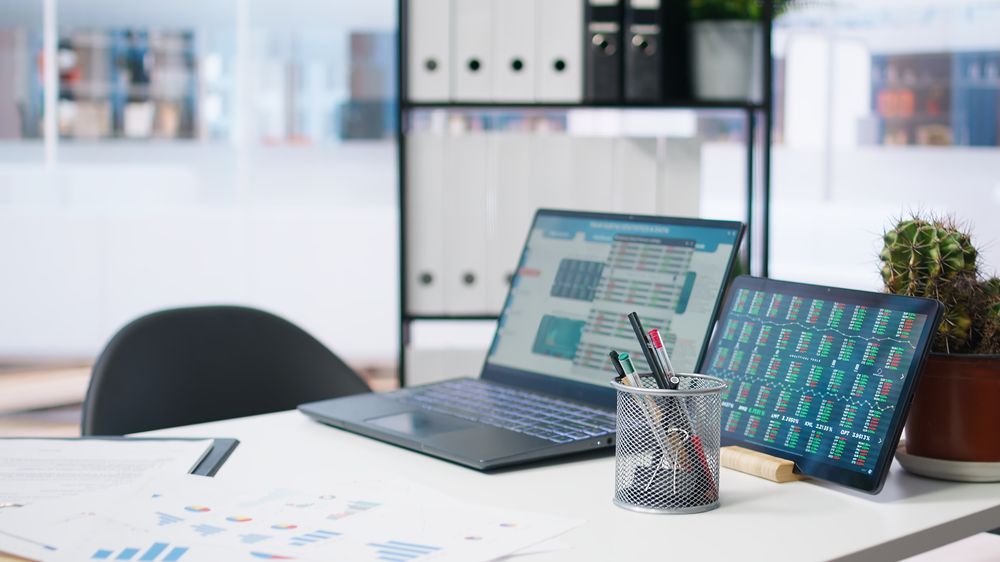 Una computadora portátil está sobre un escritorio al lado de una tableta.