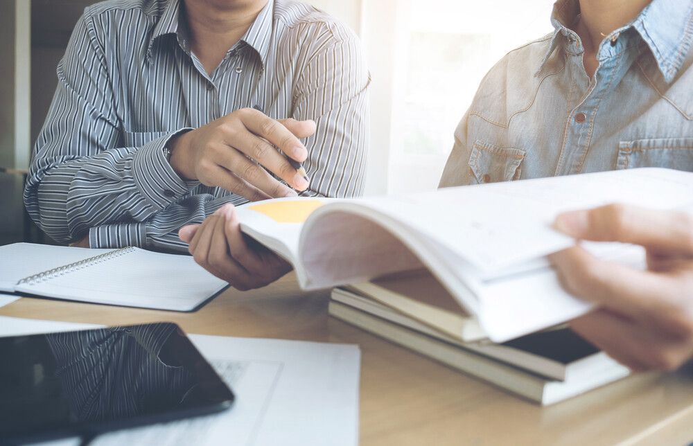 Un grupo de personas está sentada en una mesa leyendo libros.