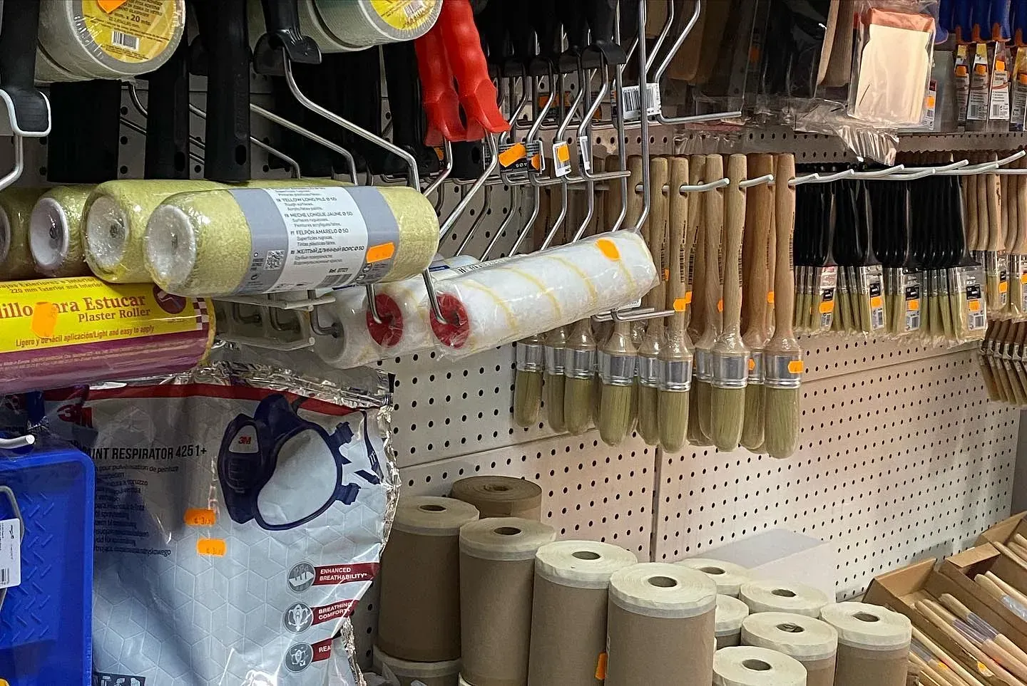 Una exhibición de rodillos y pinceles de pintura en una tienda.