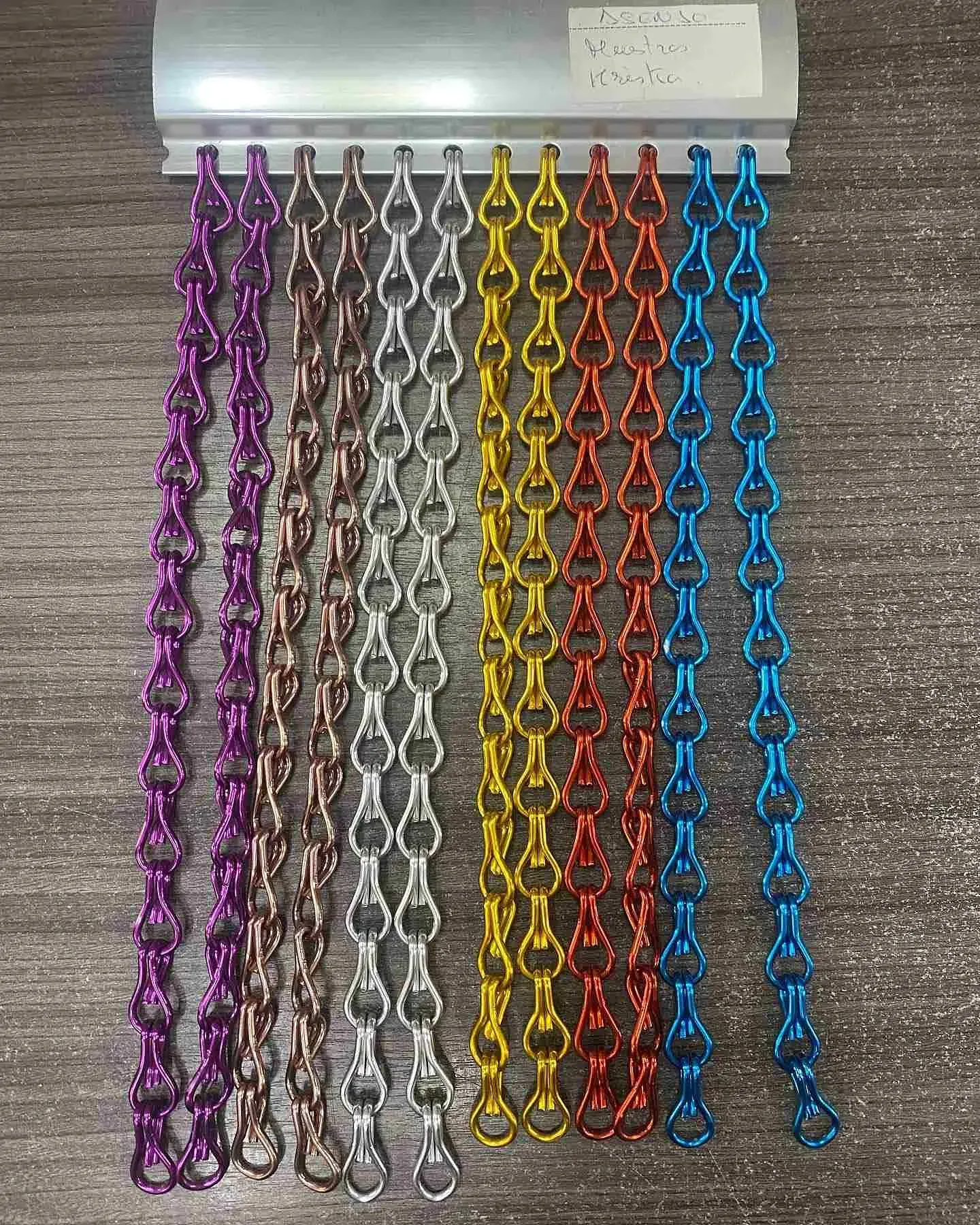 Un montón de cadenas de colores están colocadas encima de una mesa de madera.