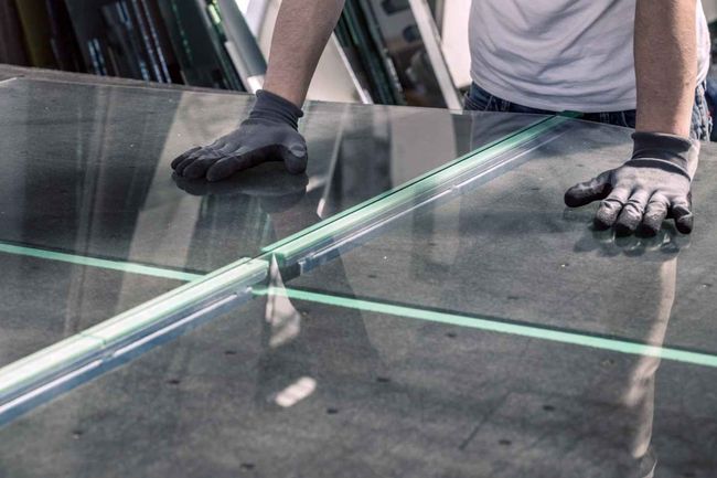 Ein Mann schneidet ein Stück Glas auf einem Tisch.