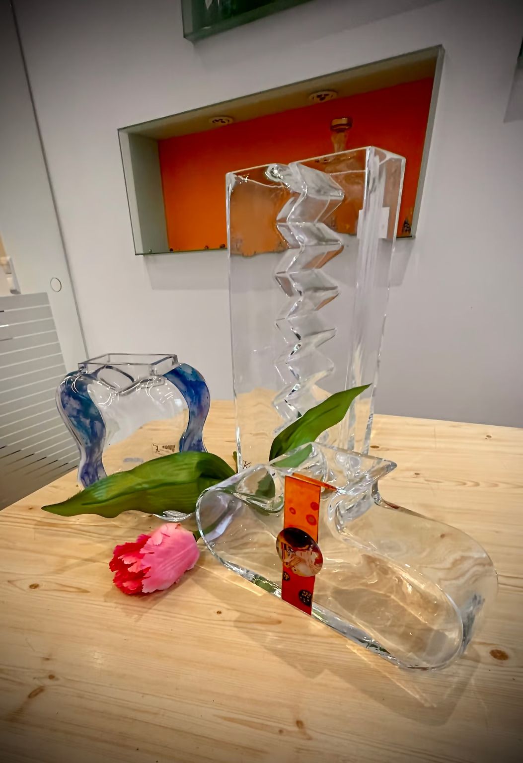 Auf einem Holztisch steht eine Glasvase mit einer Blume darin.