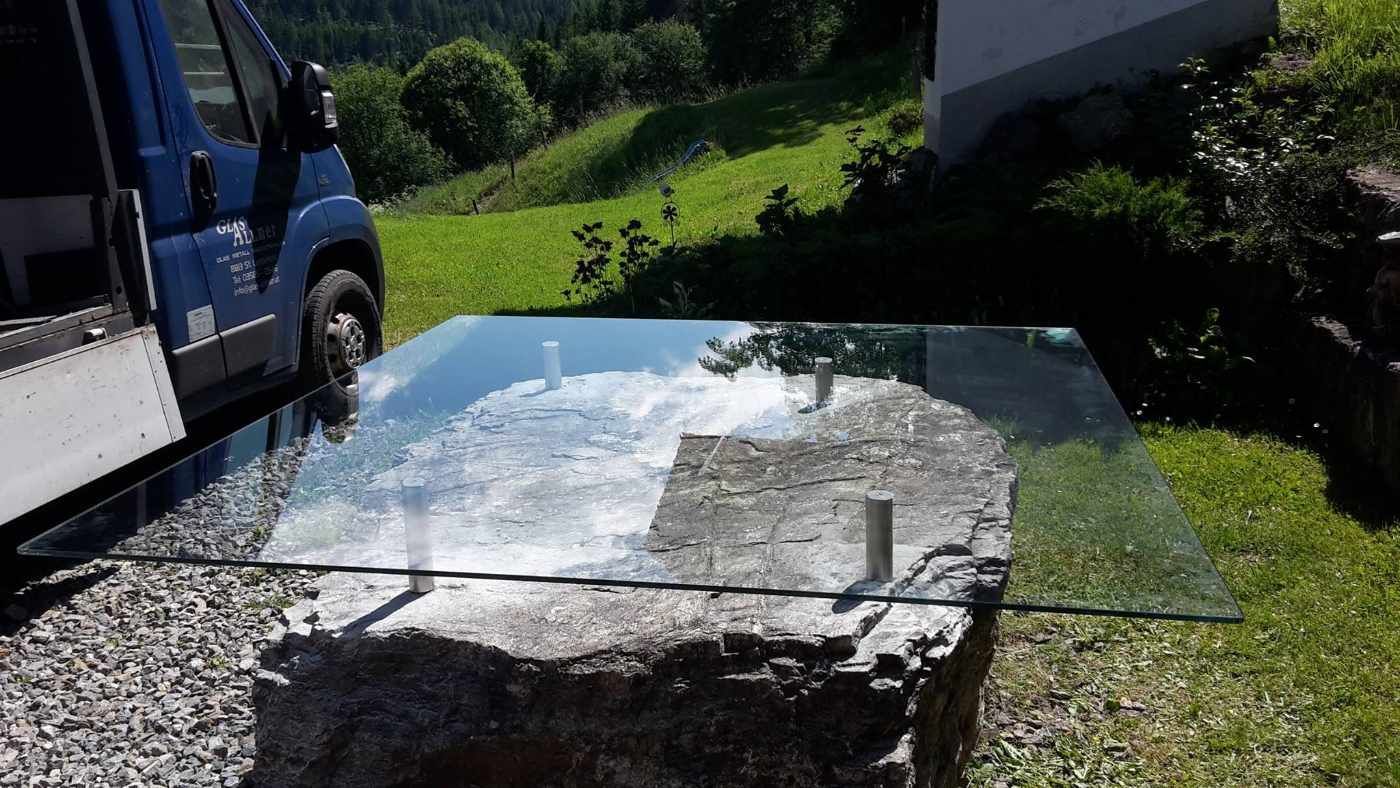Auf einem großen Felsen steht ein Glastisch.