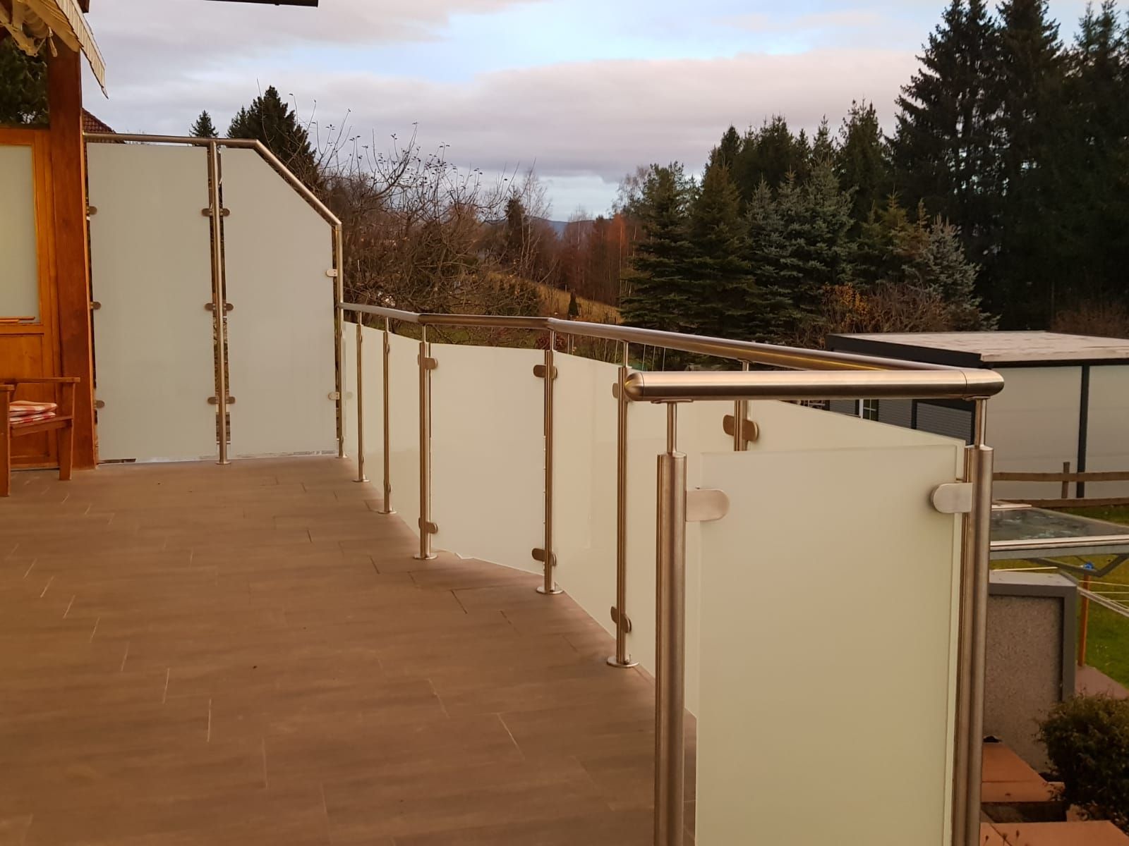 Ein Balkon mit Edelstahlgeländer und weißen Glaswänden.