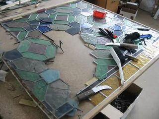 Auf einem Tisch wird ein Buntglasfenster gebaut